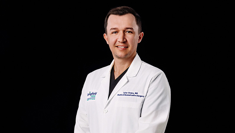 Male physician smiling in front of photo backdrop