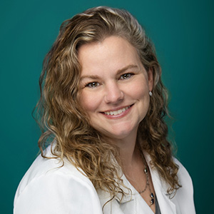 Female emergency medicine physician smiling in front of green background