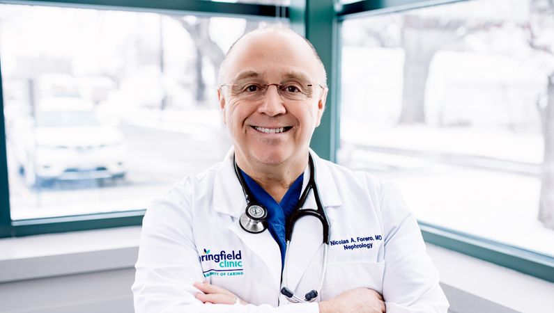Man in white doctors coat smiling in front of a window