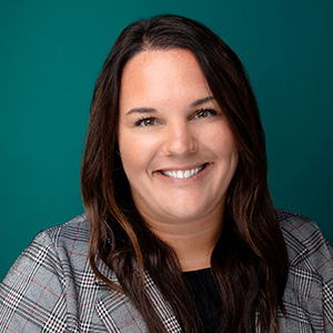 Female nurse with dark hair smiling in a professional headshot.