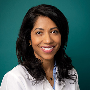 Female endocrinologist doctor in white medical coat smiling for professional headshot.