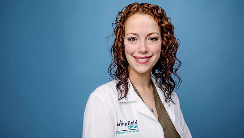 Female nurse practitioner smiling in white medical coat.