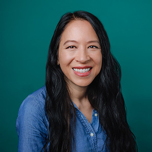 Female pediatrician with long dark hair smiling in professional headshot.