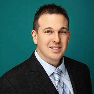 Male emergency medicine physician smiling in front of green background