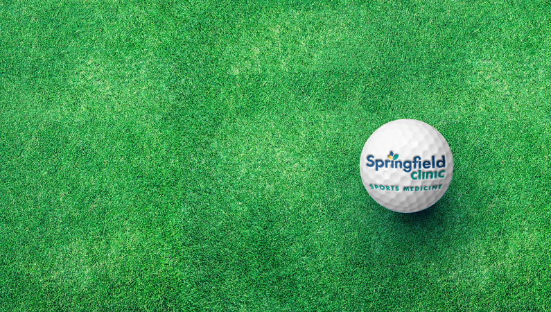 Golf ball with Springfield Clinic logo on green grass.