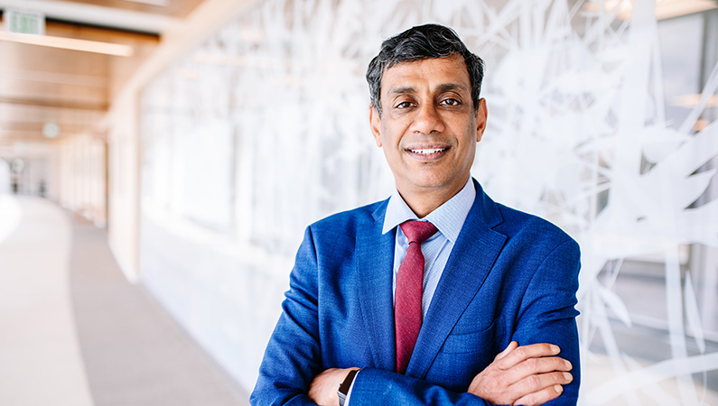 Man smiling in front of a clear wall with tree decals.