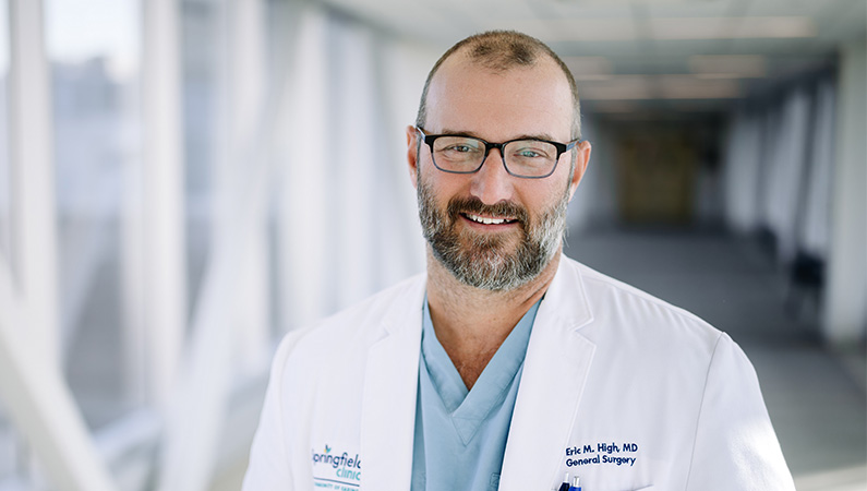 Male physician smiling in long hallway