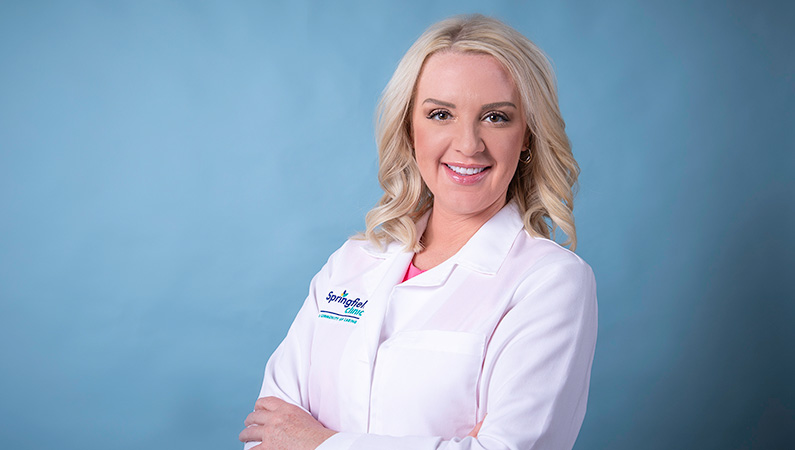 Woman smiling in front of a blue backdrop.