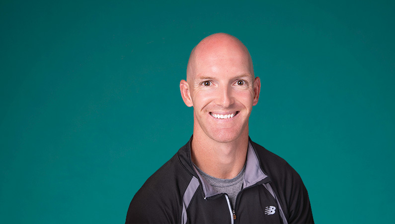 Male smiling in front of green background