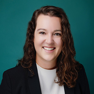 Female smiling in professional headshot in front of blue photo backdrop