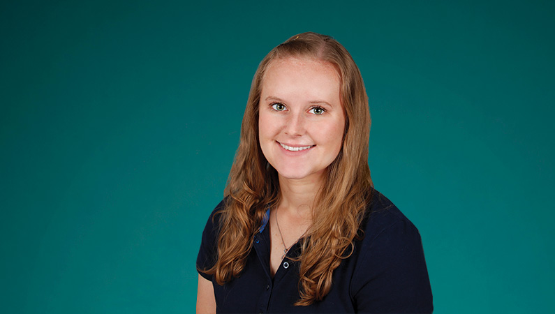 Female with light hair smiling in front of green background