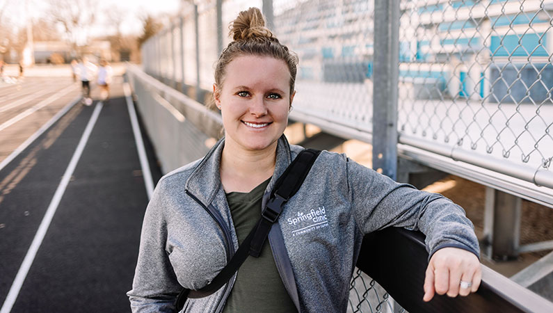 Female athletic trainer smiling with outdoor track in background