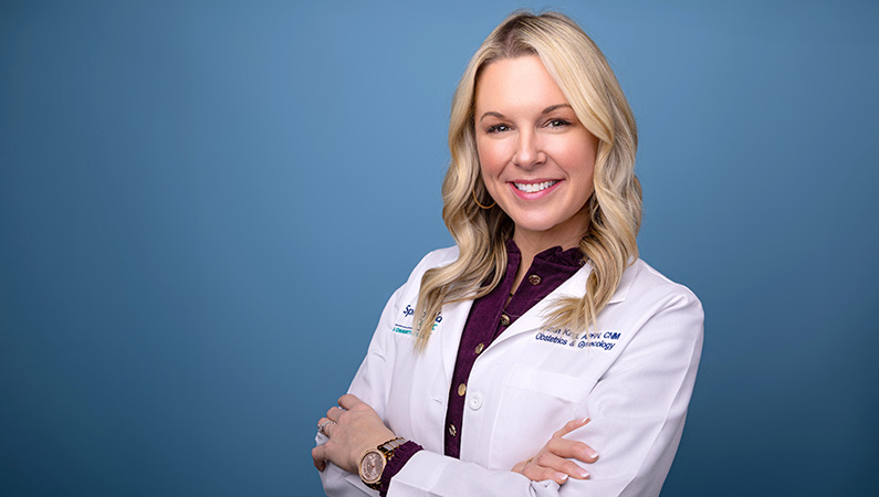 Female in white medical coat posing in front of light blue background