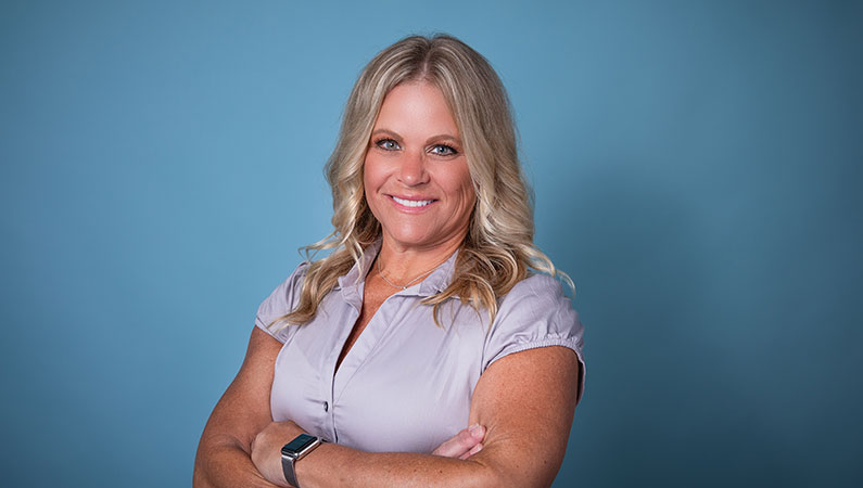 Female with blonde hair smiling studio setting with light blue background