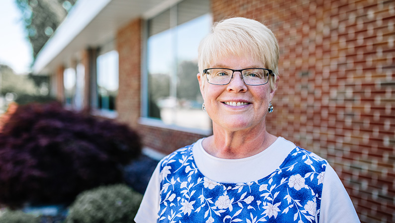 Woman smiling in front of doctor's office building.