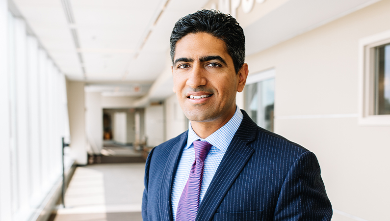 Male wearing suit and tie smiling in walkway