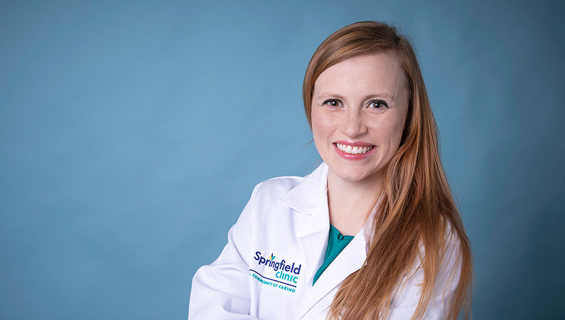 Woman smiling in front of blue background.