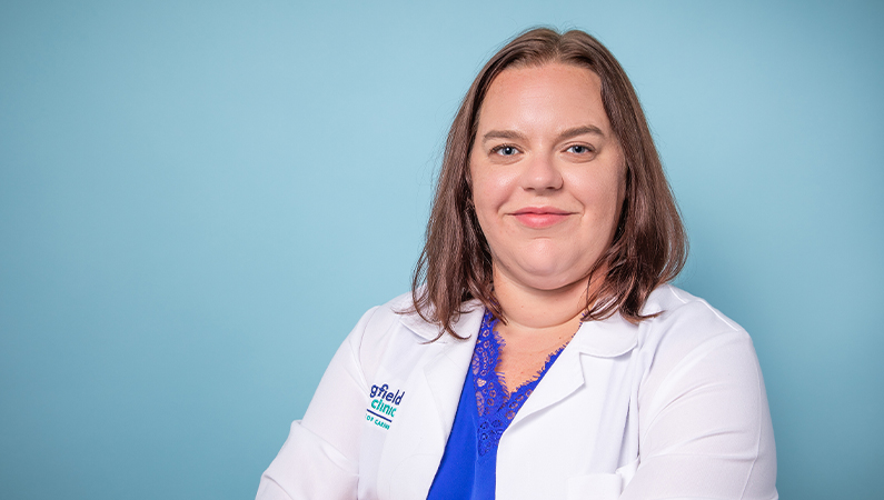 Female nurse practitioner smiling in white medical coat.
