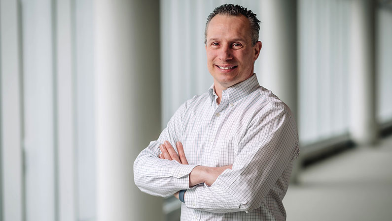 Male doctor smiling in a naturally lit hallway.