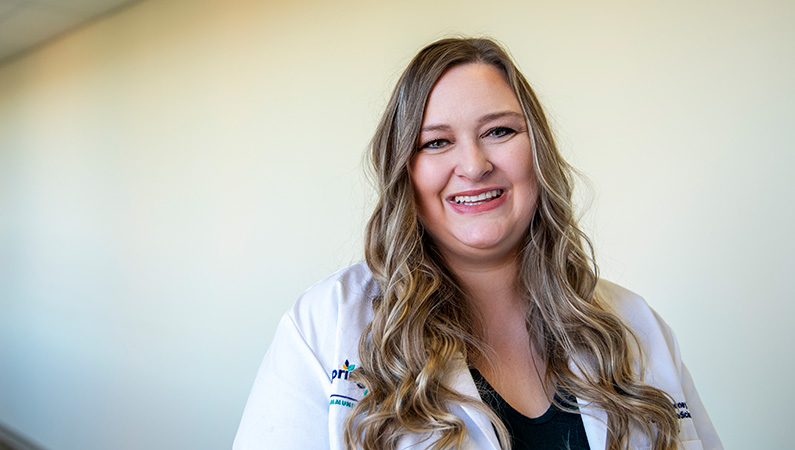 Woman smiling in a well lit hallway.