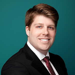 Male trauma surgeon smiling in professional headshot.