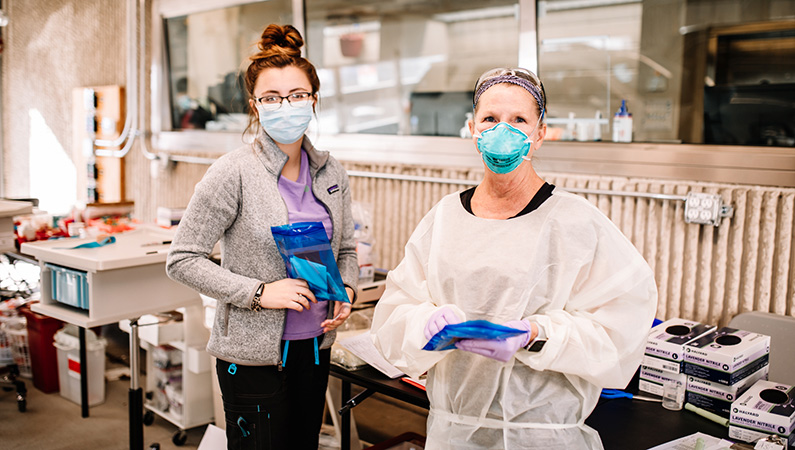 Two lab workers with medical masks on in the drive-up lab office.