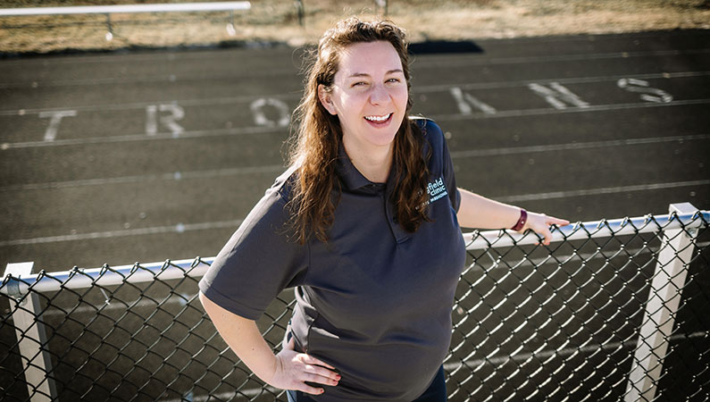 Female athletic trainer smiling with outdoor track in background