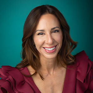 Female nurse practitioner smiling in front of blue background