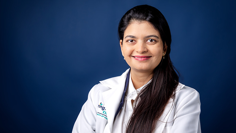 Female bariatric surgeon physician smiling in front of blue photo backdrop.