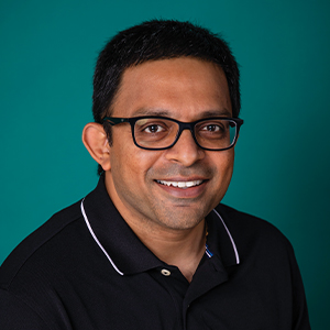 Male hospital doctor smiling with a blue background.