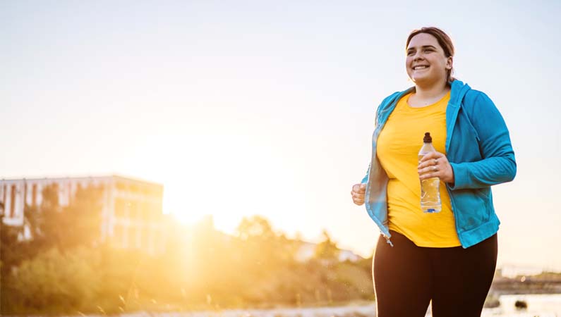 Female running on a sidewalk with water bottle in hand.