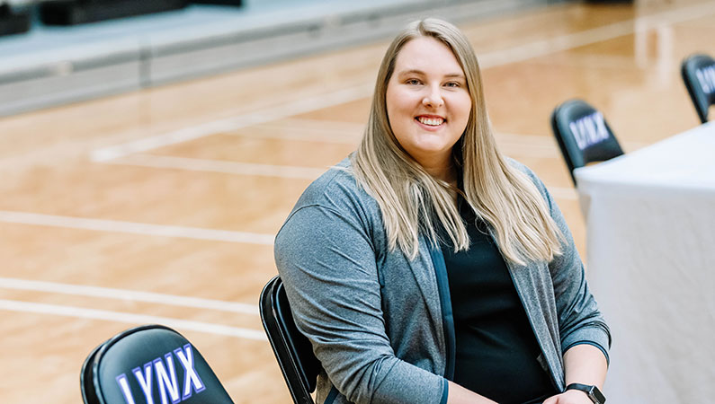Female athletic trainer sitting in chair smiling in school gym setting