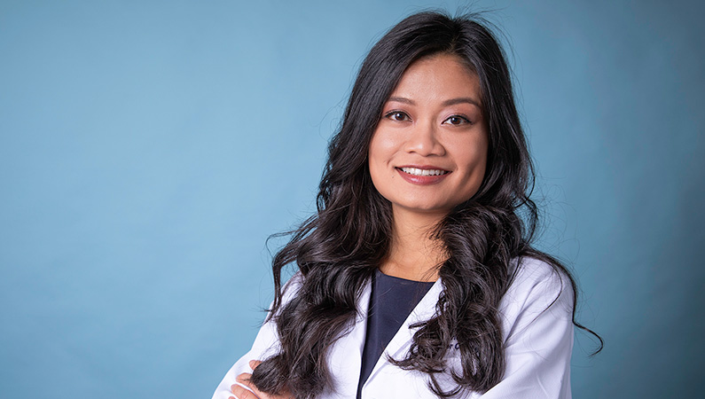 Woman smiling in front of a blue backdrop.