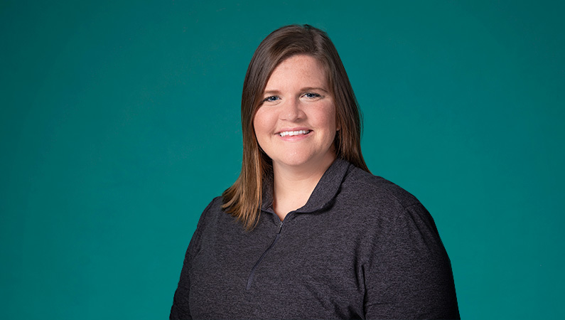 Female with short dark hair smiling in front of green background
