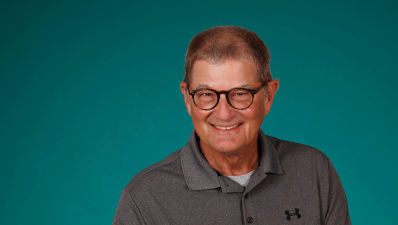 Male wearing glasses smiling in front of green background