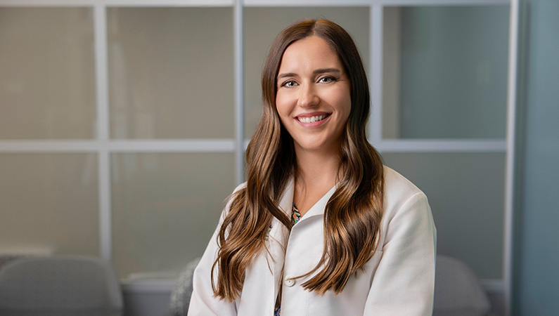 Female wearing white medical coat smiling in medical clinic office
