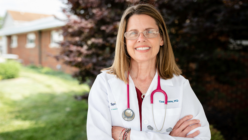 Female internal medicine doctor smiling in outdoor setting.