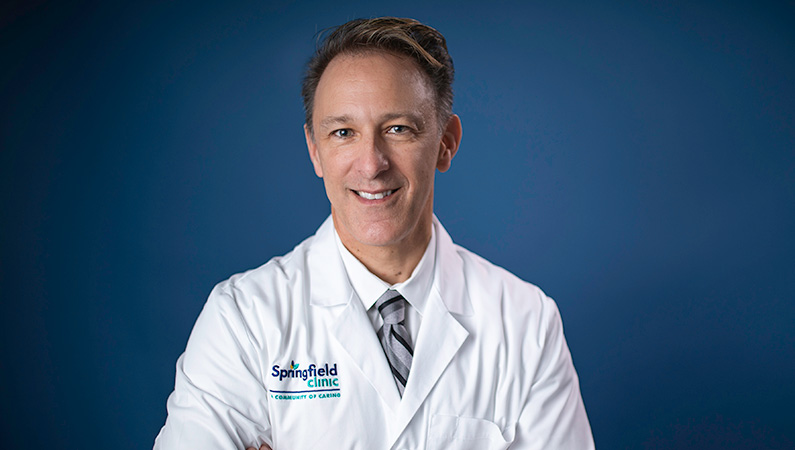 Man smiling in front of a blue backdrop