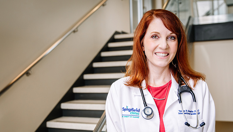 Female with red hair smiling in a well-lit stairwell
