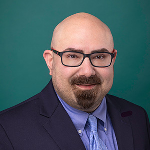 Male critical care doctor smiling in professional headshot.