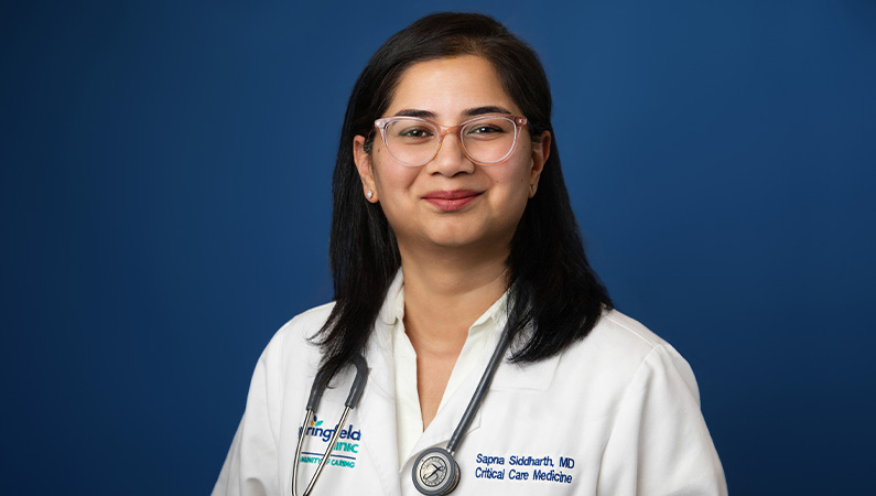 Female physician smiling in front of blue background