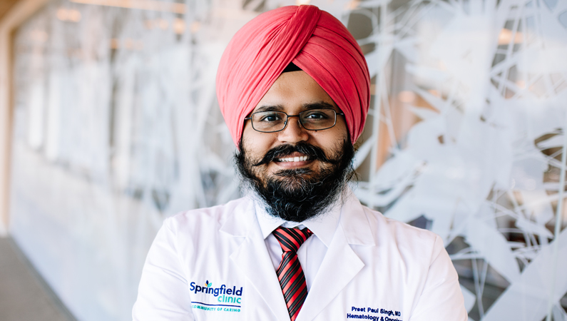 Man smiling in front of a clear wall with tree decals.