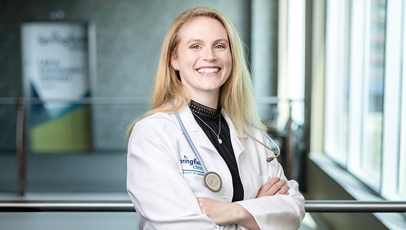 Female internal medicine doctor in white coat smiling in a doctor's office.