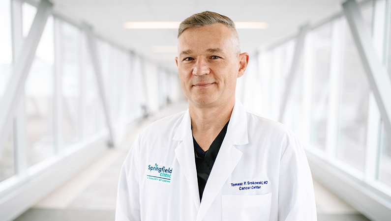 Male cancer doctor posing in a naturally lit hallway.