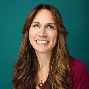 Female emergency medicine physician smiling in front of green background