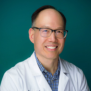 Male orthopedic surgeon smiling in professional headshot.