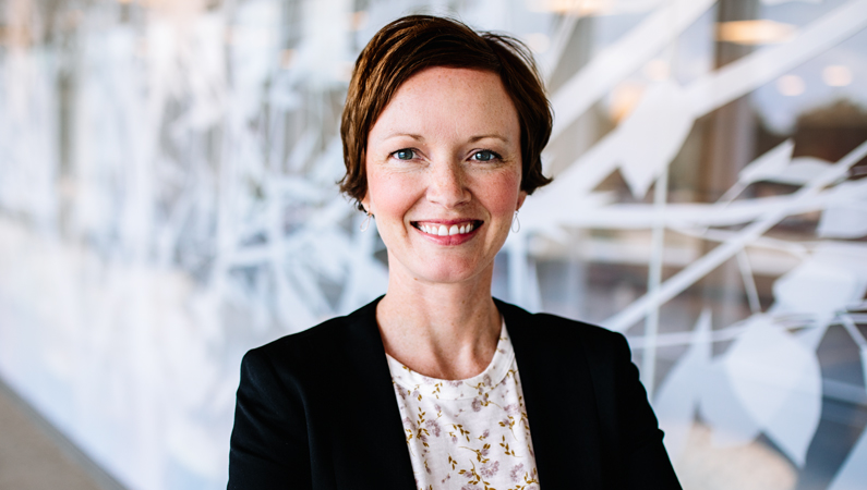 Woman smiling in front of a clear wall with tree decals.