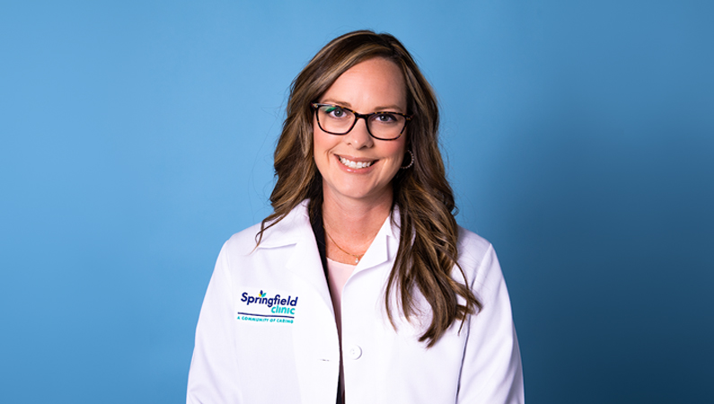 Woman smiling in front of a blue backdrop.