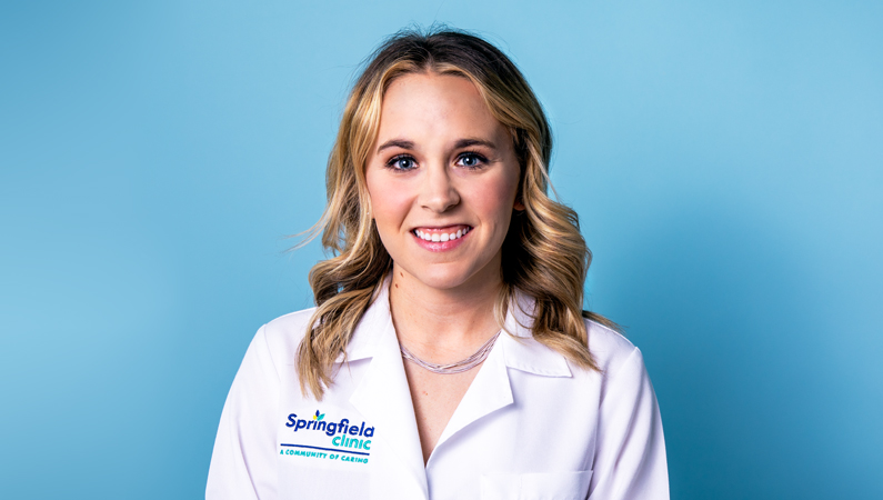 Woman smiling in front of a blue backdrop.